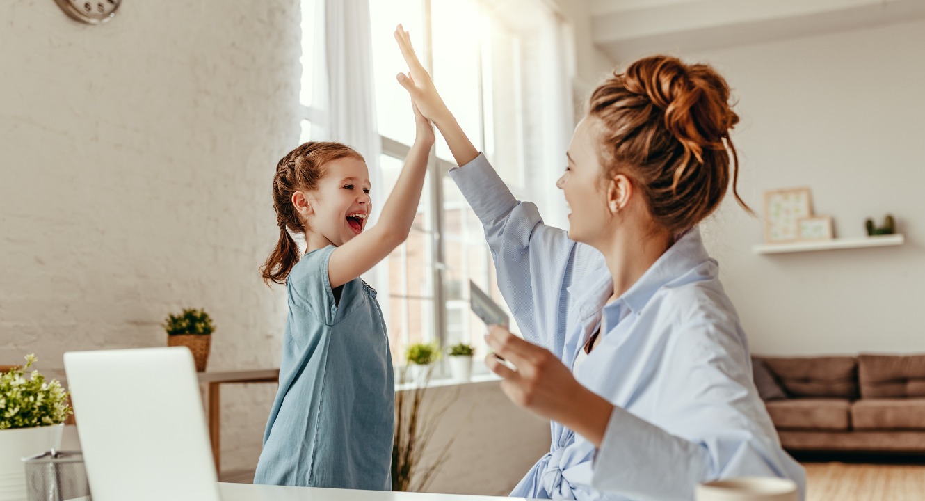 happy woman giving daughter high five while purchasing something online with debit card